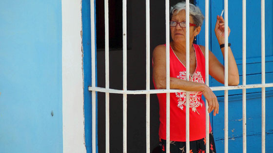 Frau mit Zigarette schaut in Trinidad, Kuba aus einem Fenster