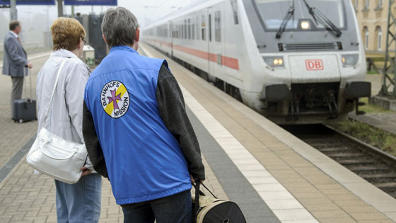Mitarbeiter der Bahnhofsmission begleitet einen Fahrgast zum Zug.